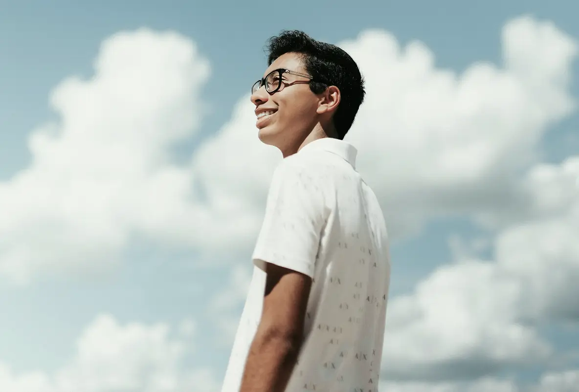 Person standing calmly under a bright sky.